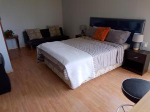 a bedroom with a large bed and a couch at Fisherhaven Guest House in Hermanus