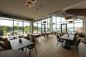 a restaurant with tables and chairs and windows at Kedi Hotel Papenburg in Papenburg