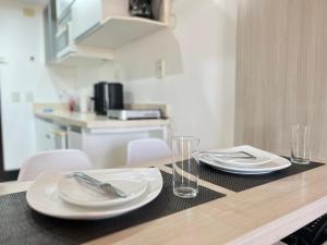 a table with plates and glasses on top of it at Lake Side Resort Flat Beira Lago 5 minutos do centro de Brasília in Brasília