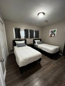 two beds in a small room with wooden floors at Modern 3 Bedroom Ranch House in Newark