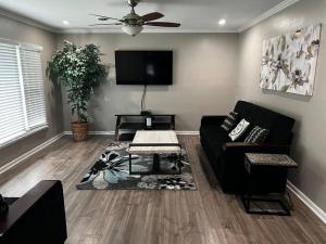 a living room with a black couch and a tv at Modern 3 Bedroom Ranch House in Newark