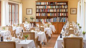 un ristorante con tavoli e sedie bianchi e libri di Atrio a Estreito da Calheta