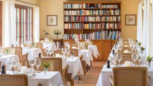 um restaurante com mesas brancas, cadeiras e livros em Atrio em Estreito da Calheta