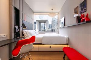 een slaapkamer met een bed, een bureau en een rode stoel bij citizenM Paris La Défense in Nanterre