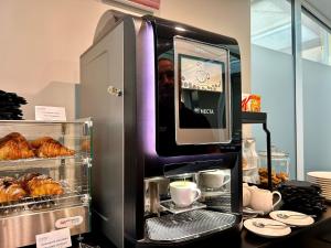 a coffee machine with cups and pastries on a counter at BB Hotels Smarthotel Duomo in Milan