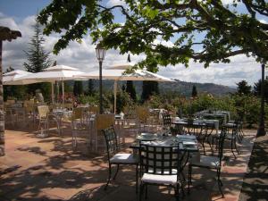 een patio met tafels, stoelen en parasols bij Les chambres du Restaurant le Castellaras - Teritoria in Fayence