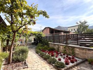 un jardín con flores rojas y blancas junto a una valla en Casa Rural Martinach - L'Amfitriona, en Sant Marti de Canals