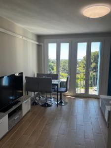 a living room with a table and chairs and a television at Appartement, vue sur l’étang, proche aéroport. in Vitrolles
