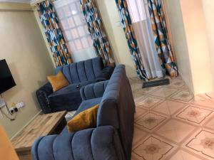 a living room with a blue couch and a tv at Mt zion penthouse in Lake View Estate