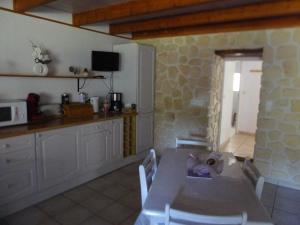 a kitchen with a table with chairs and a counter at location thezacaise in Thézac