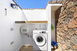 a washer and dryer in a bathroom with a stone wall at Apartamento Los 4 Nobles in Tinajo