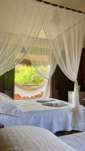 a bedroom with two beds with white curtains and a window at Casa B&B in Jijoca de Jericoacoara