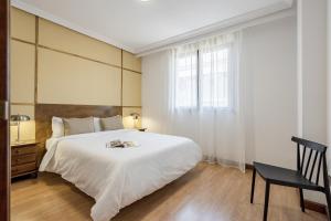 a bedroom with a large white bed and a chair at Rio Apartments by Olala Homes in Salamanca +7 photos