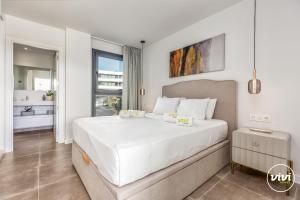 ein Schlafzimmer mit einem großen weißen Bett und ein Badezimmer in der Unterkunft ViVi Homes - Higueron Premium Wellness, Sauna, Pool & Hot tub in Fuengirola