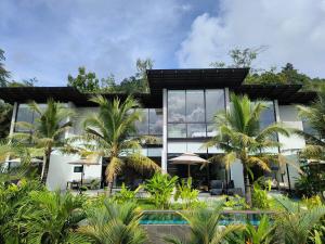 a house with a swimming pool and palm trees at Sky Lofts Phuket in Nai Yang Beach