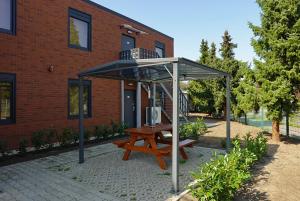 einem Picknicktisch unter einem Baldachin vor einem Gebäude in der Unterkunft Comfort Housing Apartments in Falkensee