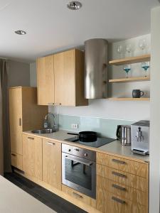 a kitchen with wooden cabinets and a stove top oven at Stylish Sea-View Apartment by the Marina in Kuressaare