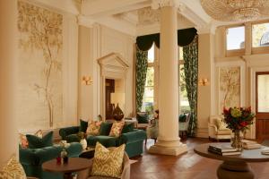 a living room with green couches and a pillar at Down Hall Hotel in Bishops Stortford +57 photos