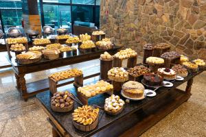 a table filled with different types of cakes and pastries at Thermas All Inclusive Resort Poços de Caldas By Nacional Inn in Poços de Caldas