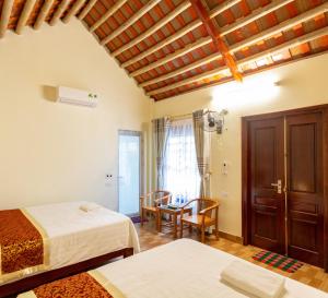 a bedroom with two beds and a table and chairs at Mai Place Homestay in Ninh Binh
