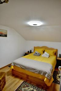 a bedroom with a large bed with yellow sheets at Casa linistita Ilie in Păltineni