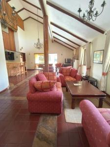 a living room with red couches and a table at Kwezi Cottage at The Great Rift Valley Lodge & Golf Resort Naivasha in Naivasha