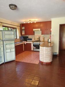 een keuken met houten kasten en een tegelvloer bij Kwezi Cottage at The Great Rift Valley Lodge & Golf Resort Naivasha in Naivasha +16 foto's