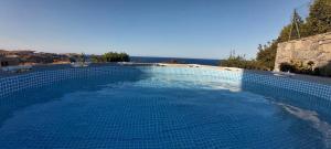 a large blue swimming pool with a view of the ocean at Βίλα Στέλλα Ιωάννης in Agia Pelagia