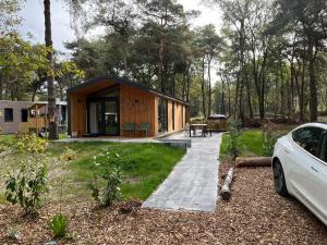 a cabin in the woods with a car parked next to it at Hella in Haarle