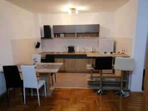una cucina con un tavolo di legno e sedie bianche di Apartman Ana a Apatin