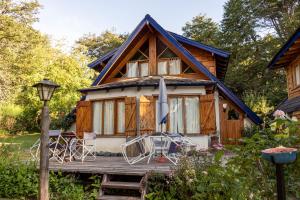 a cabin with a porch and chairs on a deck at Cabañas Naxara in Villa La Angostura