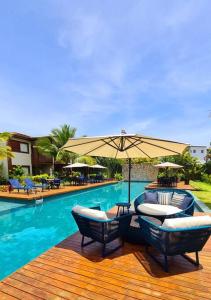una piscina con due sedie e un ombrellone di Lindo Villaggio em Barra Grande a Barra Grande