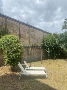 a white bench sitting in the grass next to a wall at Au cœur de Bourges in Bourges