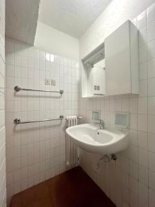 une salle de bain blanche avec un lavabo et un miroir dans l'établissement Bilocale Slalom, à Madonna di Campiglio