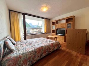 une chambre avec un lit et une grande fenêtre dans l'établissement Bilocale Slalom, à Madonna di Campiglio