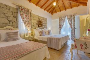 a bedroom with two beds and a stone wall at AlaNarin Konak in Alaçatı