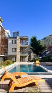 une piscine avec deux chaises longues et un bâtiment dans l'établissement Alamos de los Andes ExtraL - Andarlibre, à San Martín de los Andes