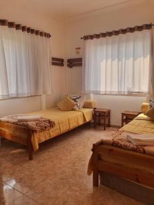 a bedroom with two beds and two windows at Zabava Odivelas in Odivelas
