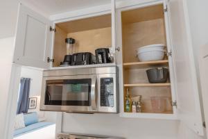 une cuisine avec des armoires blanches et un micro-ondes dans l'établissement #StayinMyDistrict Coos Bay Goldfinch Cottage, à Coos Bay