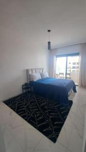 a bedroom with a blue bed and a rug at Appart familial près de la plage Val d'or in El Harhoura