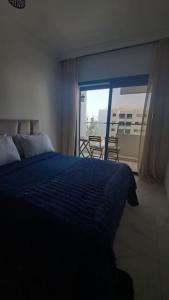a bedroom with a blue bed and a balcony at Appart familial près de la plage Val d'or in El Harhoura +10 photos