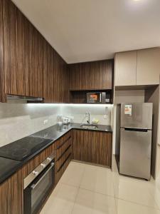 a kitchen with wooden cabinets and a stainless steel refrigerator at Departamento de lujo en EQUIPETROL in Santa Cruz de la Sierra