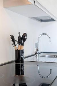 a container of kitchen utensils on a counter next to a sink at GardalandLuxuryApartment Pool & Free Parking in Ronchi