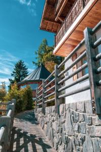 a stone wall next to a building with a fence at Chalet 4 Saisons with jacuzzi - Ovronnaz in Ovronnaz