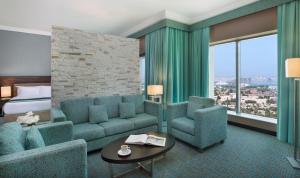 a hotel room with a couch and chairs and a bed at Atana Hotel in Dubai
