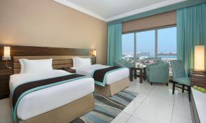 a hotel room with two beds and a table and chairs at Atana Hotel in Dubai