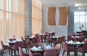a dining room with tables and chairs and windows at Atana Hotel in Dubai
