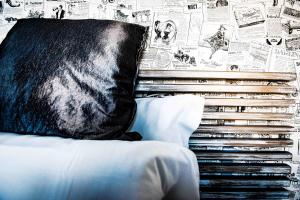 una cama con una almohada negra y una pared con carteles en Adelina Guesthouse en Roma