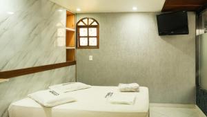 a bathroom with two beds and a tv on a wall at Midway Hotel in Rio de Janeiro