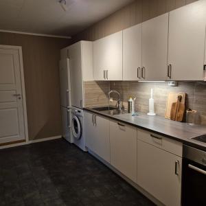 a kitchen with white cabinets and a washer and dryer at Leilighet Ytrebyen Vadsø in Vadsø +3 photos